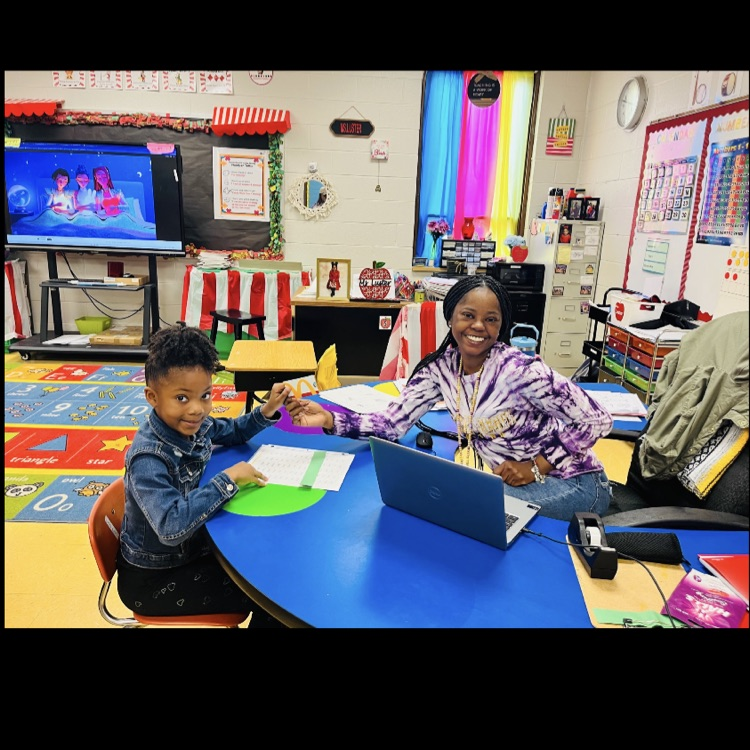 A picture of Ms. Luster and a student because her class won the song of the week.