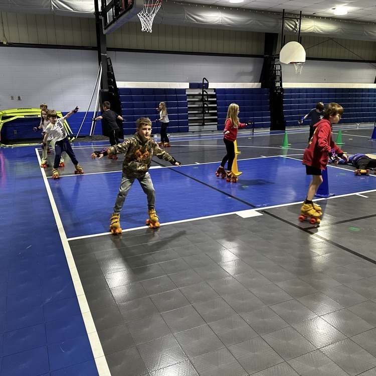 Students roller skate inside a school gym.