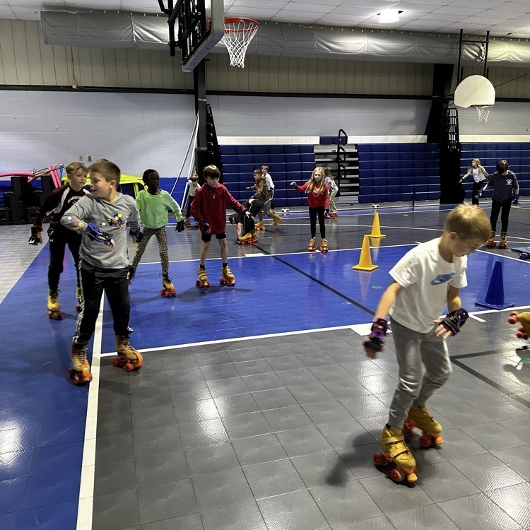 Students roller skate inside a school gym.