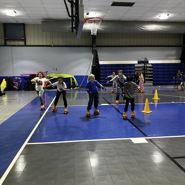 Students roller skate inside a school gym.