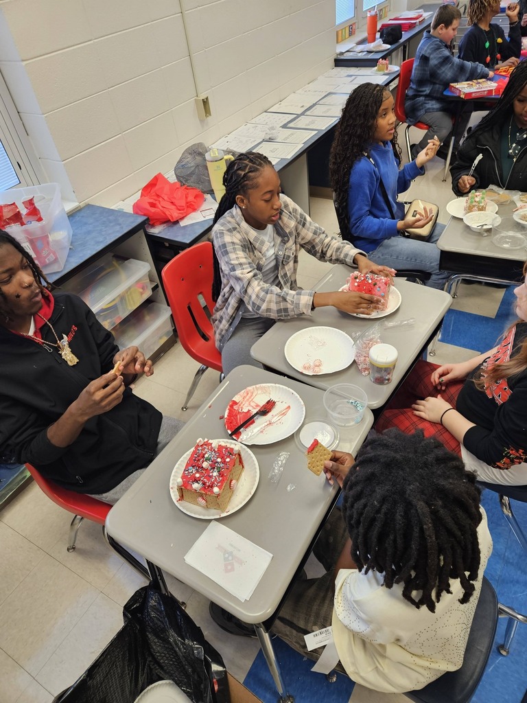 Minor Community School and Minor High School students sit together at a table and make gingerbread houses.