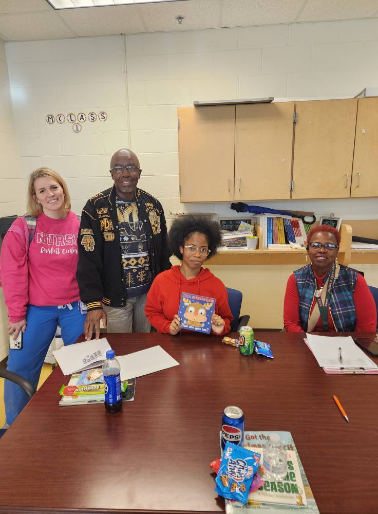 Adults and Center Point High School students stand and sit together for a photo and smile.