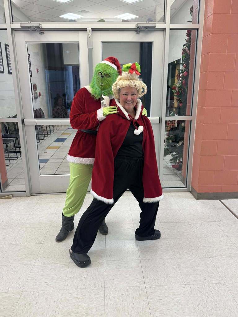 A woman dressed like a "Who" poses next to someone wearing a Grinch costume.