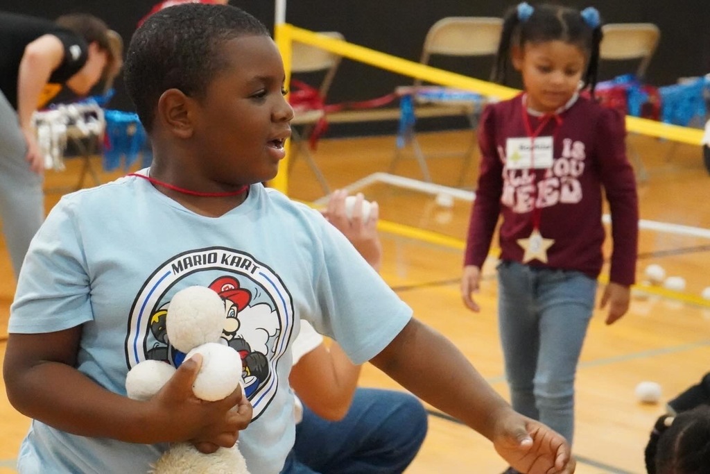 A student holds snowballs made of fabric while playing in a school gym.