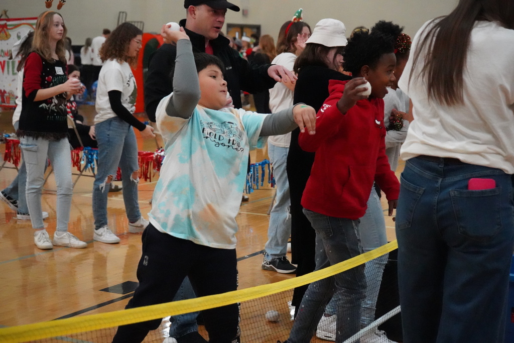 A student throws snowballs made of fabric inside a school gym.