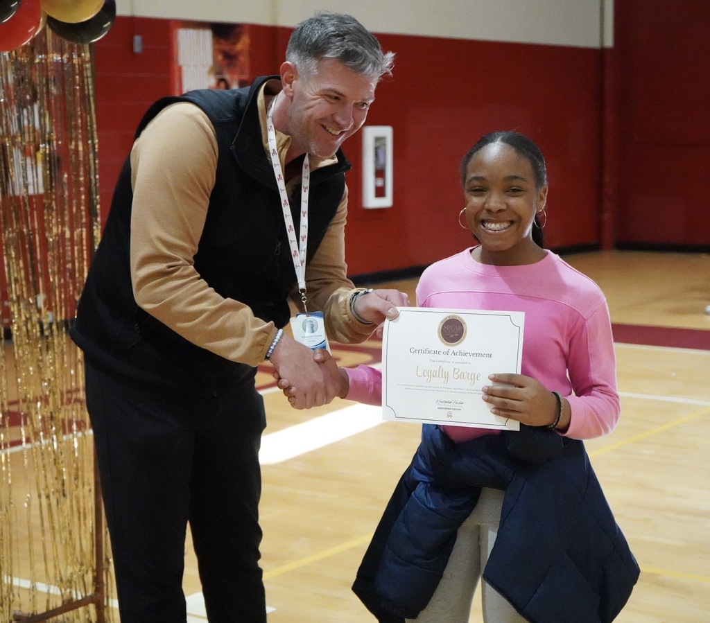 Rudd Middle School's principal hands a certificate to a student during an award ceremony held in the school gym.