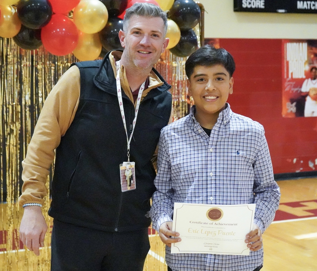 Rudd Middle School's principal stands next to a student for a photo during an award ceremony held in a school gym.