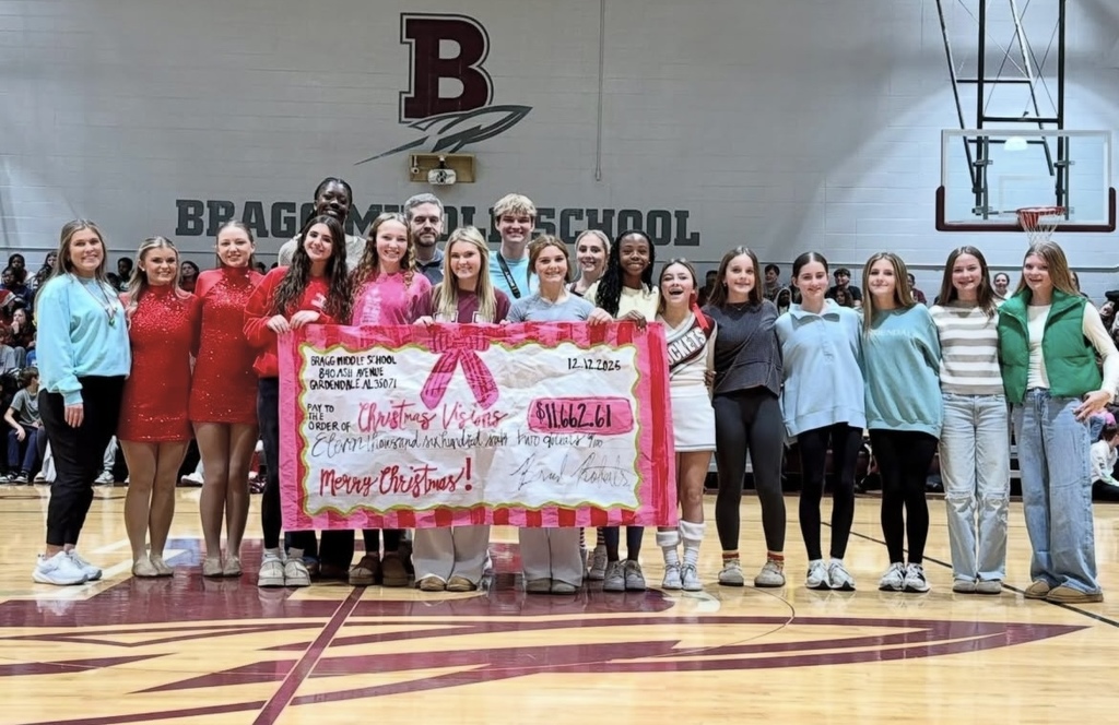 Image is from the Bragg Middle School Christmas Visions Pep Rally inside Bragg's gym. Here, students pose with a large piece of paper made to look like a check. It's showing the amount of money students raised for Christmas Visions. The total was $11,662.61.