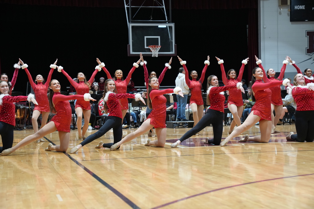 Image is from the Bragg Middle School Christmas Visions Pep Rally inside Bragg's gym. In the photo, dance team members are performing in red costumes.