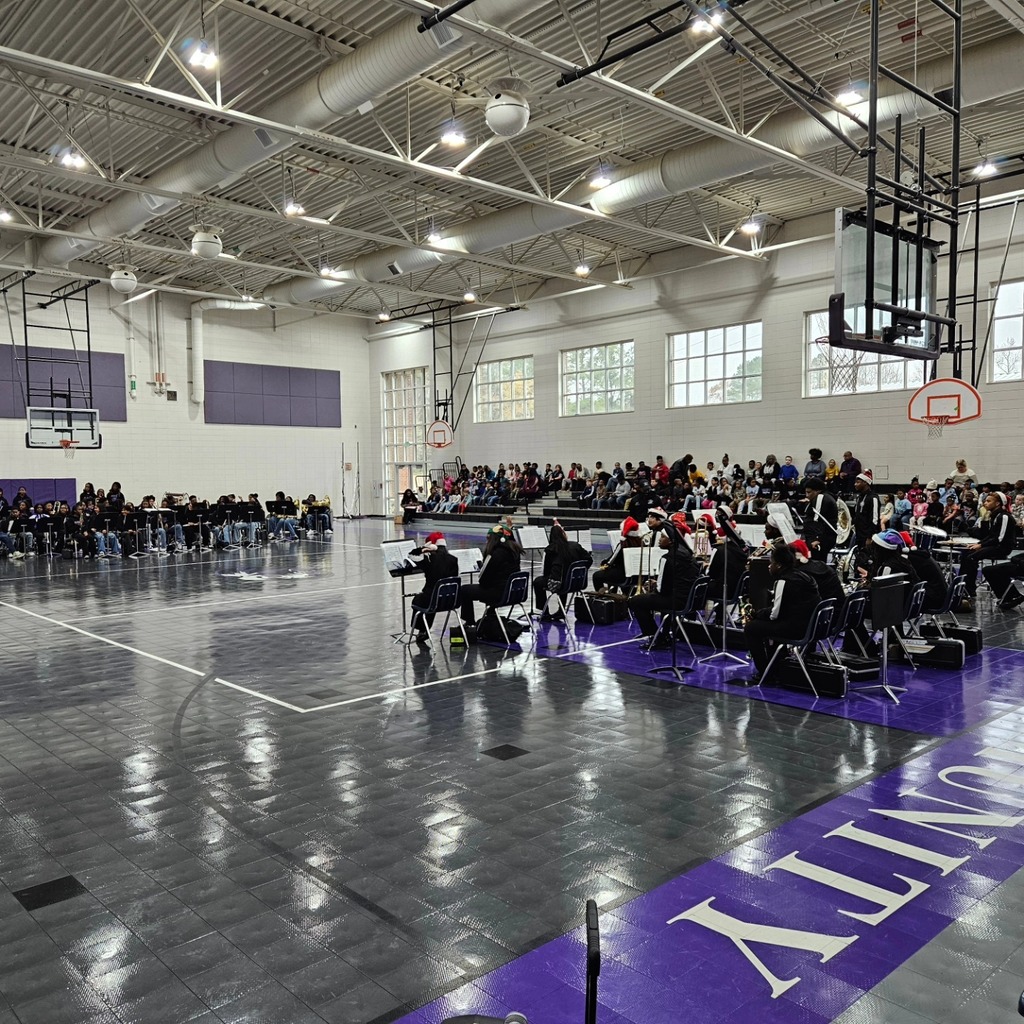 Image is of a band performing for students inside a school gym.