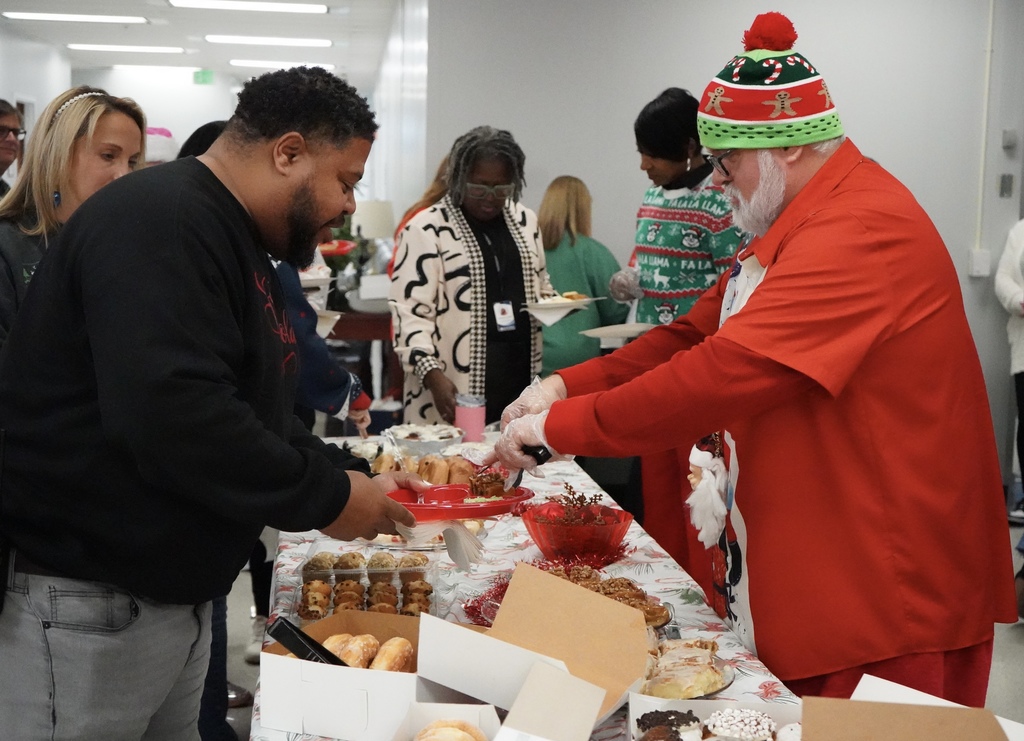 A man wearing holiday attire serves another man food at a holiday breakfast.