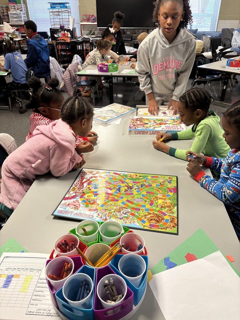 Students sit at tables in a classroom and play a game of candyland.