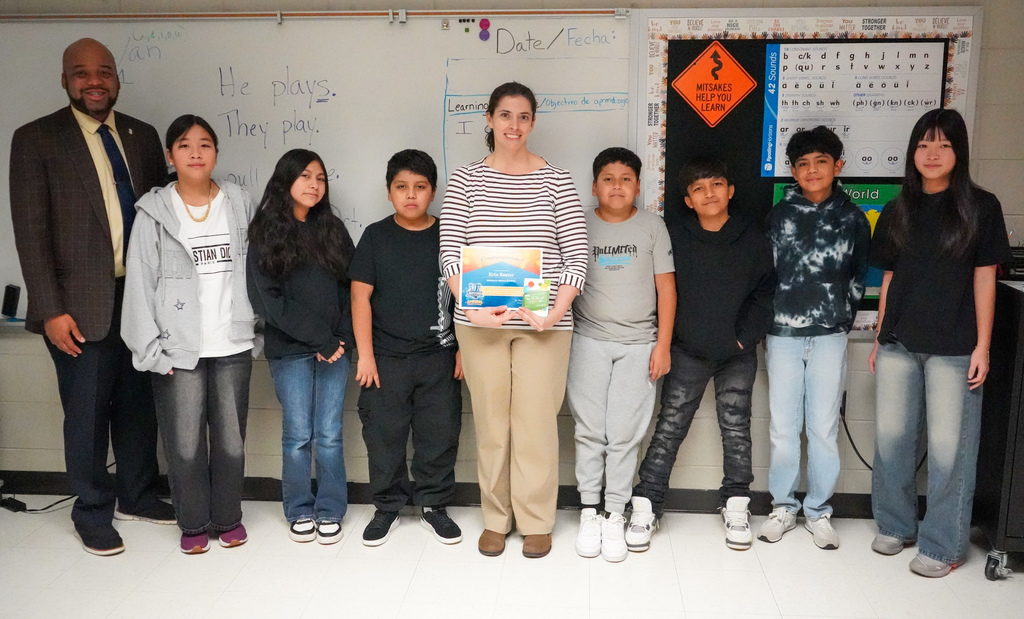 Irondale Middle School principal Mr. Marvin Carter and teacher Ms. Erin Baxter stand with seven students and pose for a photo inside Ms. Baxter's classroom. Ms. Baxter holds a JEFCOED Strong Award in her hands. 