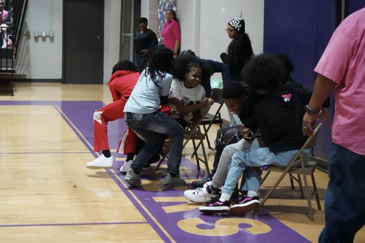 Minor Middle School students smile as they try to sit down in chairs during a competitive game in the school gym.
