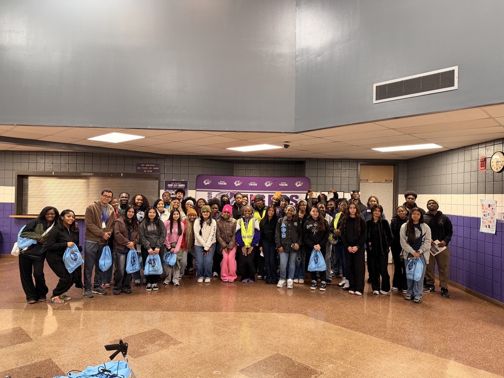 A group of community cleanup volunteers stand together for a photo inside Minor High School.