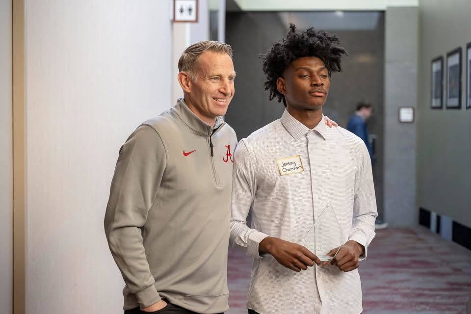 Shades Valley High School student Jeremy Chatman poses next to Alabama Basketball Coach Nate Oats for a photo. Jeremy holds an award.