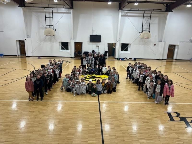 Students at Bagley Elementary School stand  for a photo in the gym making the shape of the number 101.