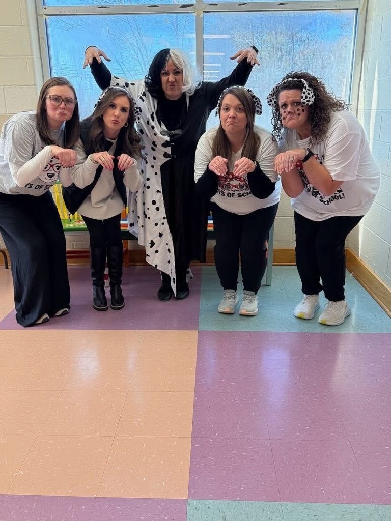Employees at Bagley Elementary stand together for a photo in the school hallway. They're dressed like dogs and Cruella de Vil from the movie "101 Dalmations."