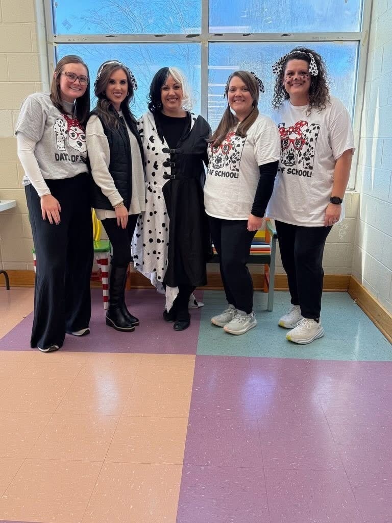 Employees at Bagley Elementary stand together for a photo in the school hallway. They're dressed like dogs and Cruella de Vil from the movie "101 Dalmations."