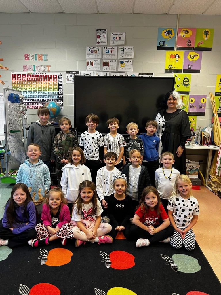 Students and a teacher at Bagley Elementary School dress like dogs from 101 Dalmations and pose for a photo in a classroom.