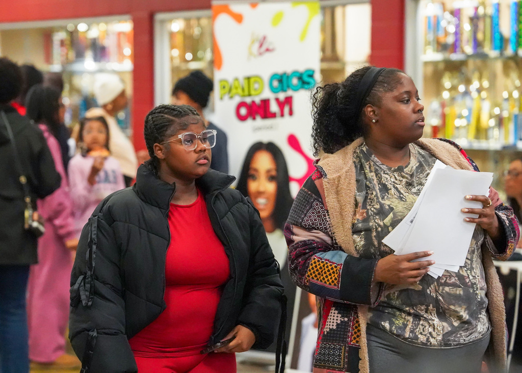 A pair of women who appear to be mother and daughter walk down a school hallway during a community event. 