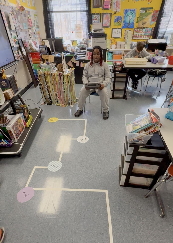 A students holds a device and is trying to navigate a robot through a pathway. 