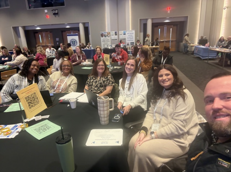 JEFCOED Career Coaches sit at a table and smile while attending the annual Career Coach Retreat at the University of Alabama.