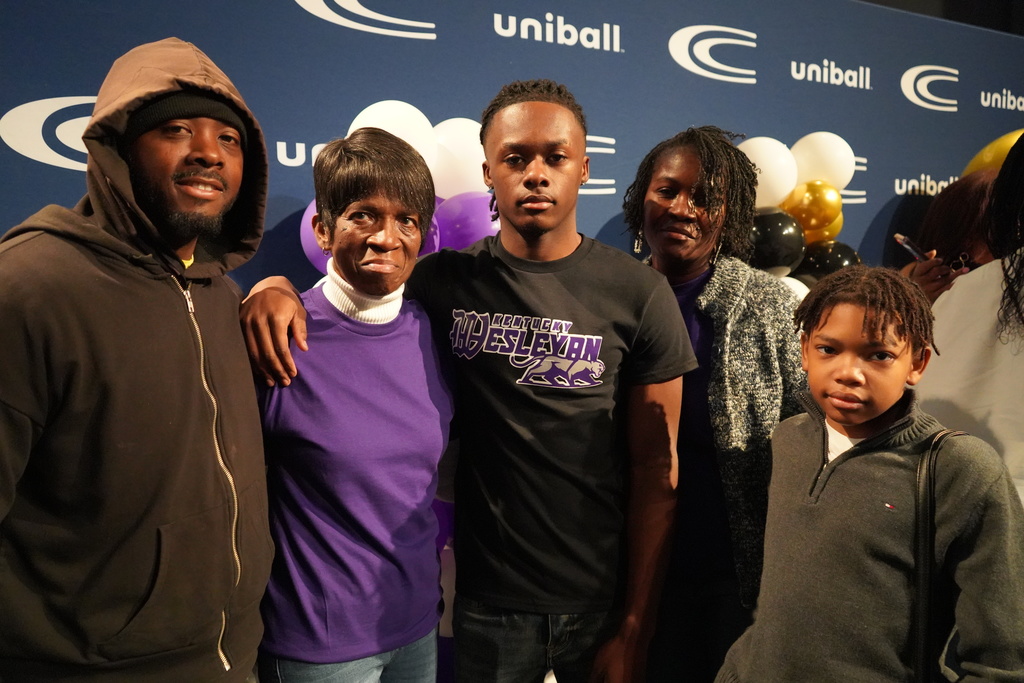 Clay-Chalkville High School student Brayden Butler poses for a photo with two women, a man and a child. They all stand in front of a photo backdrop with Clay-Chalkville High School's logo on it.