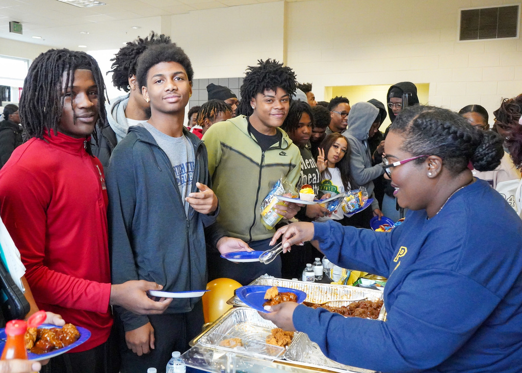 A group of high school students are being served foot by a smiling parent during a National Signing Day event at McAdory High School. 