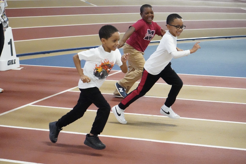 Three students smile as they race down a track at the Birmingham Crossplex.