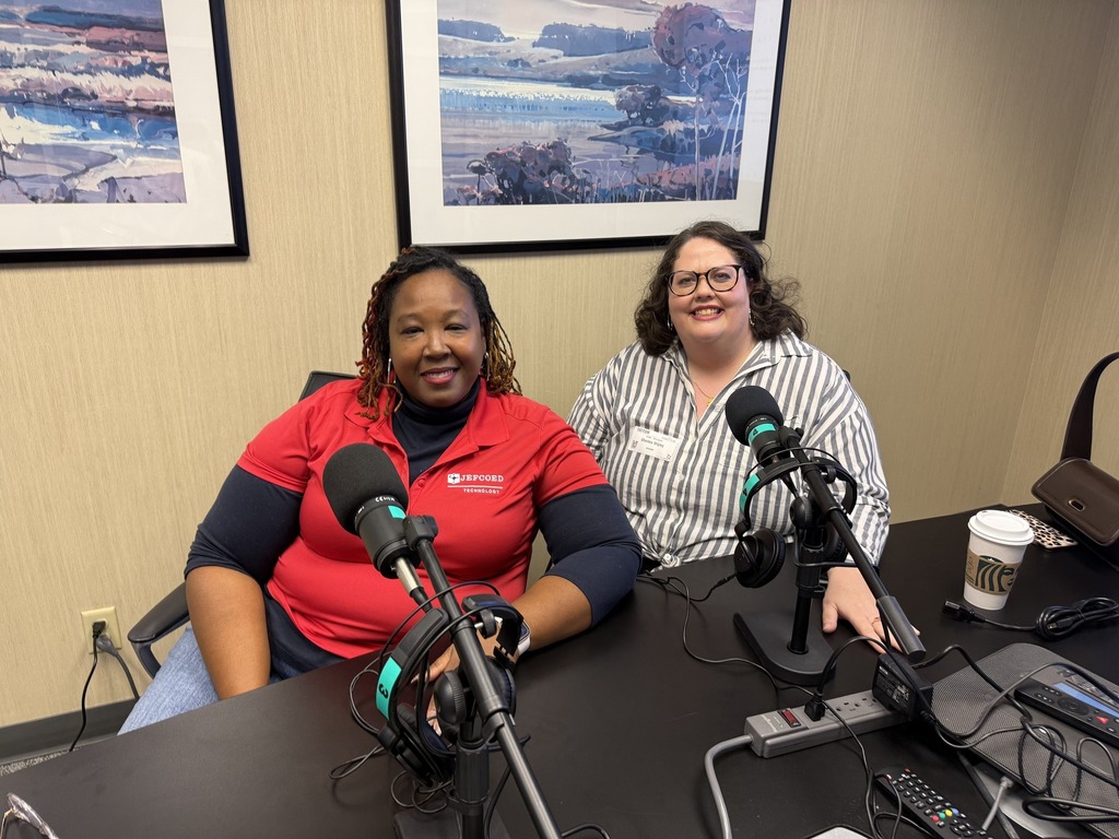 JEFCOED's Delfreda Coleman and Charlsie Wigley sit at a table with microphones and and headphones on it.