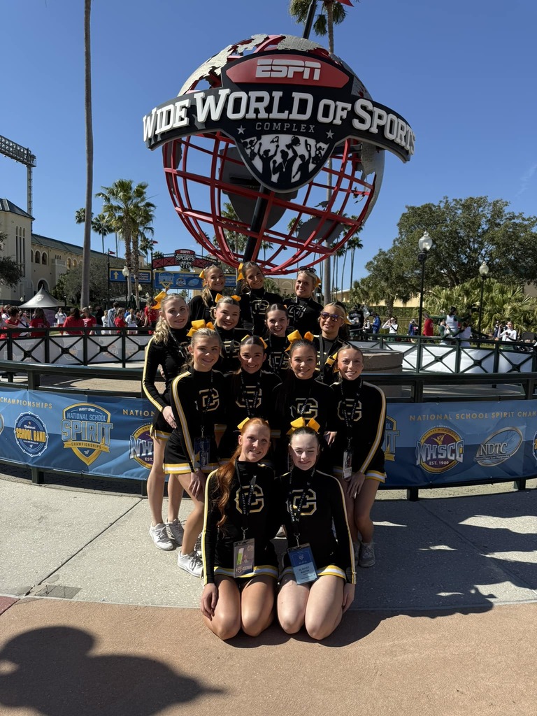 Corner High School cheerleaders stand together for a photo in their cheer uniforms. They're outdoors in front of a structure shaped like a globe that says ESPN Wide World of Sports.