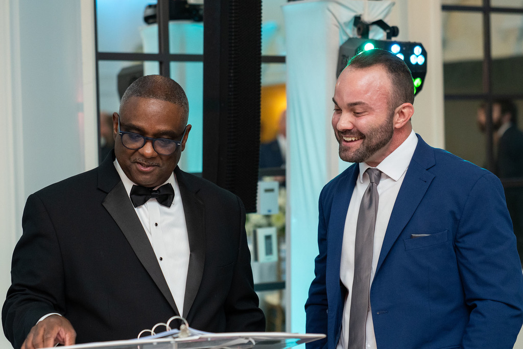 JEFCOED Superintendent Dr. Walter Gonsoulin and news anchor Stoney Sharpe stand at a podium togehter. They look down at a binder and smile.