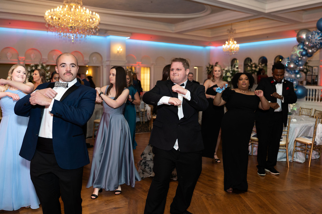A group of people dance on a dance floor in a ballroom.