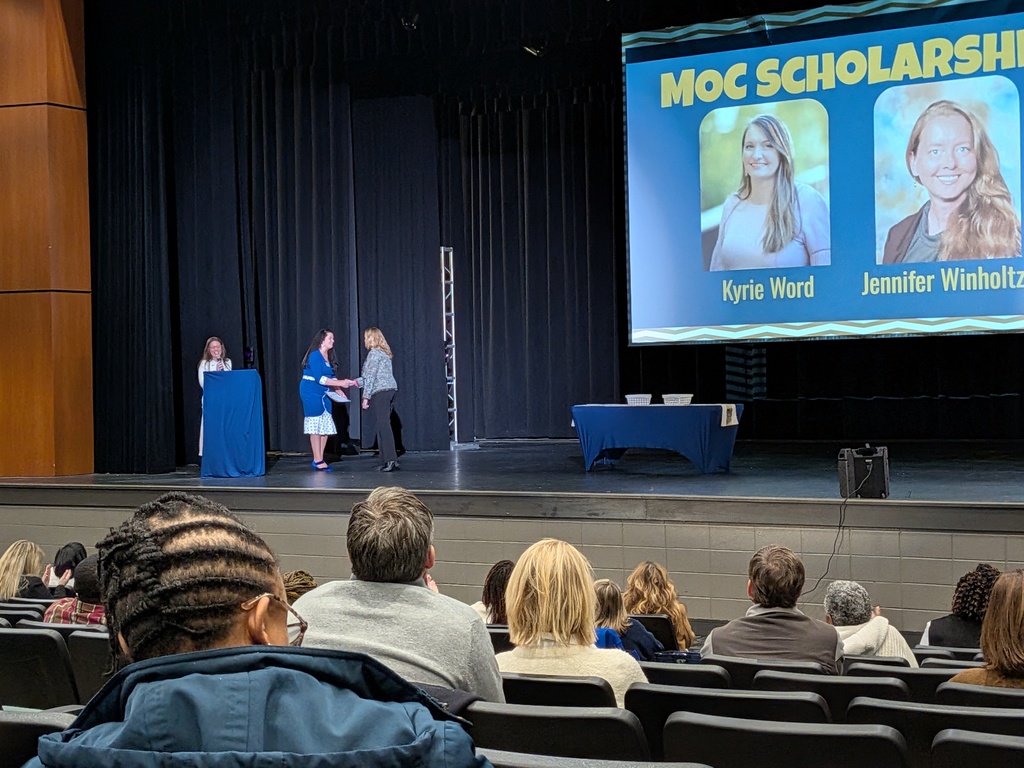 Jennifer Winholtz shakes a woman's hand on stage as she receives a scholarship to complete her Maintenance of Certificate.