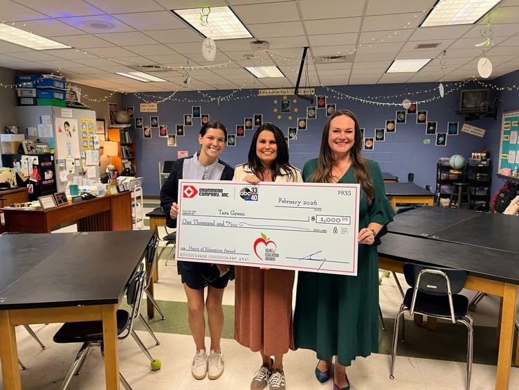 teacher holding check from award