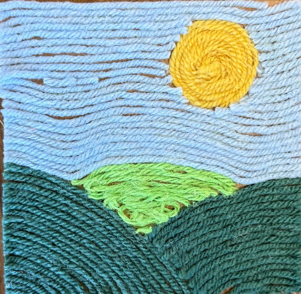 A piece of art made using blue, yellow and green yarn to create a sky, sun and valley. 