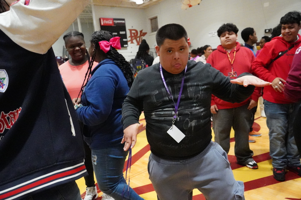 A student dances at a school dance while other students dance around him in the background.