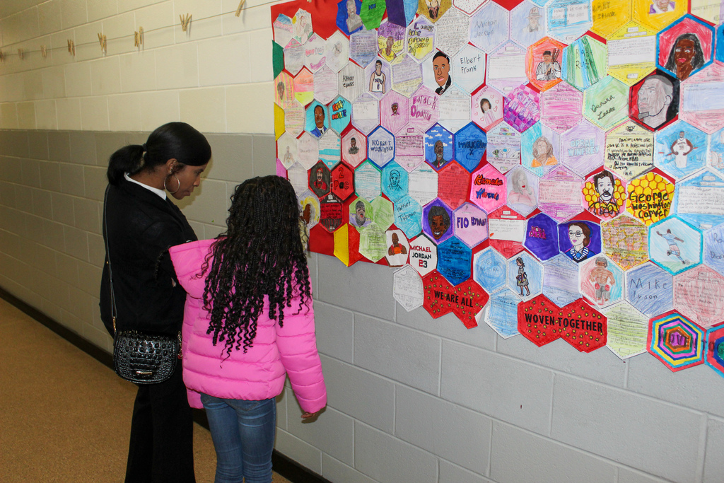 A woman and a girl look at student-made art work on the wall of a hallway inside Johnson Elementary School.
