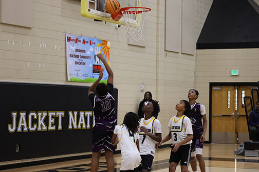 A Minor Middle School boys basketball player shoots a ball toward a hoop during a game against McAdory Middle School's team.