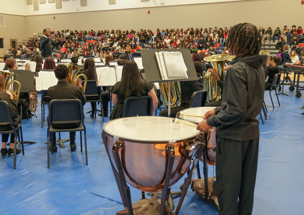 Band members perform during Fultondale High School's Black History Month program. They play in the middle of the gym while students watch from the bleachers.