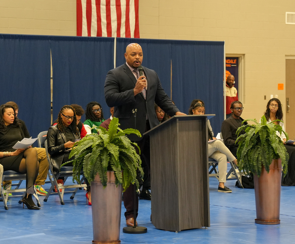 Fultondale High School's principal speaks into a microphone while standing at a podium during Fultondale High School's Black History Month program.