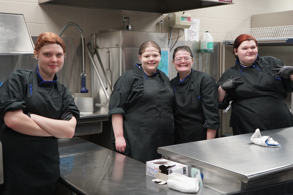 JEFCOED Culinary Arts students smile for a photo while standing inside a kitchen.