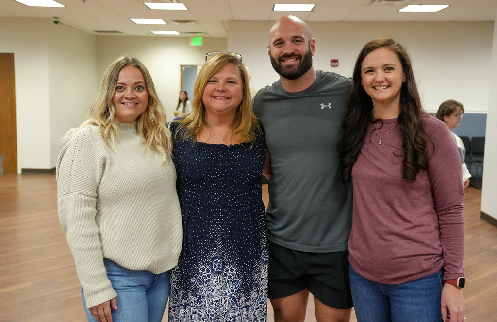 Three women and a man stand together for a photo. They stand in a room inside the Jefferson County Schools Central Office Building.