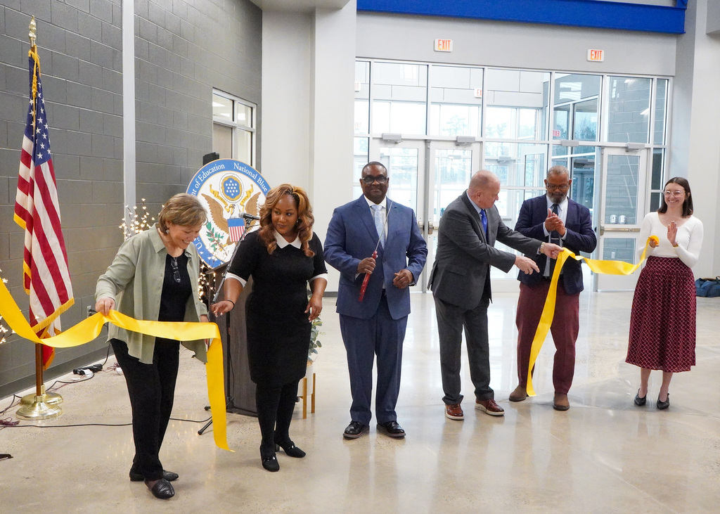 Superintendent Dr. Walter Gonsoulin, board members, and the principal of Jefferson County International Baccalaureate School stand together for a ribbon cutting ceremony. Dr. Gonsoulin holds scissors as the ribbon falls to the ground.