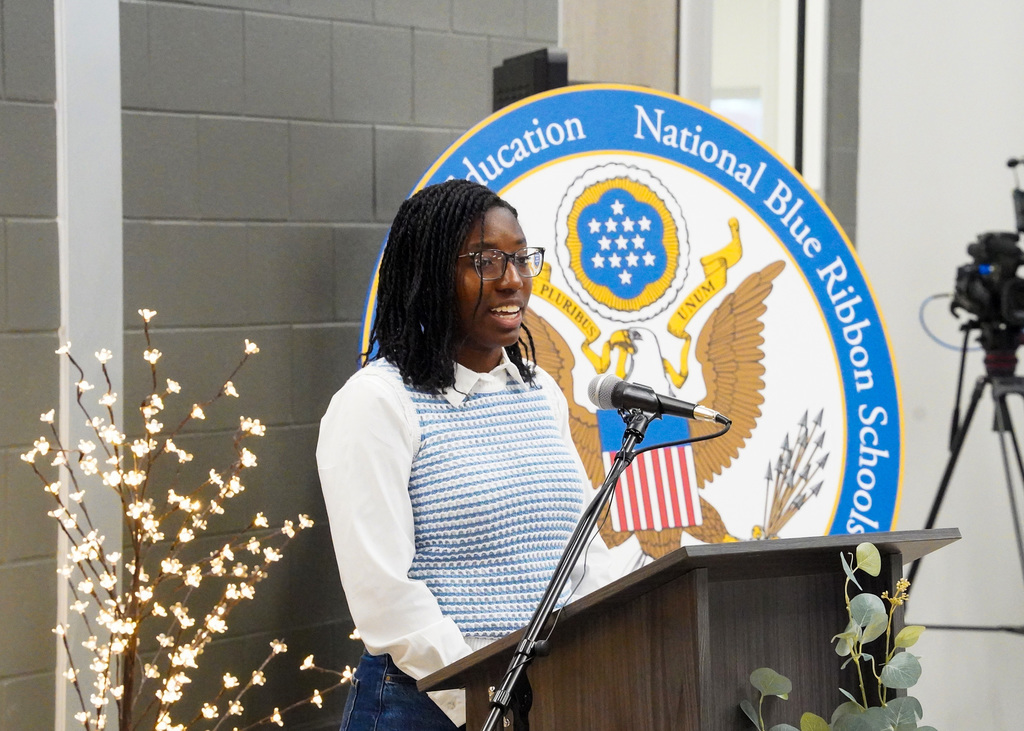 A student speaks into a microphone during the ribbon cutting ceremony for the new JCIB building.