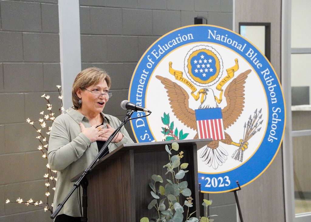 JCIB's principal Lori Lightsey speaks into a microphone at a podium during the JCIB ribbon cutting ceremony.