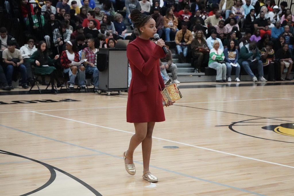 A student speaks into a microphone while performing a theatrical piece during McAdory Middle School's Black History Month program.