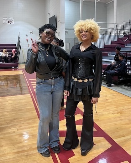 Two women dressed up for a Black History Program. One is holding up a peace sign.