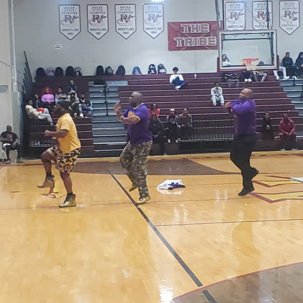 Three men perform a step routine during a school assembly.